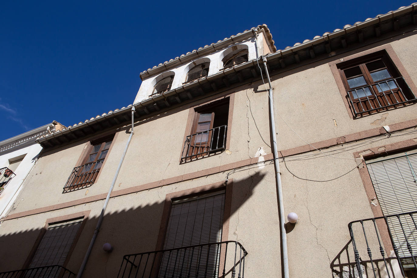 Imagen secundaria 2 - Arriba, el alcalde de Santa Fe, Juan Cano, señala la grieta en la Puerta de Sevilla. Abajo, más grietas en la Puerta de Sevilla y en una vivienda del casco histórico santaferino. 