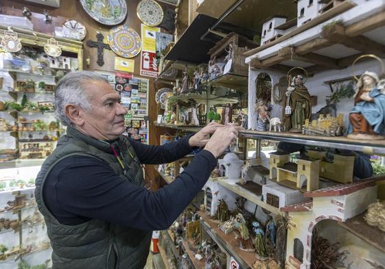 Miguel López Mariscal monta sus piezas de belén en los estantes de su tienda de la Alcaicería.