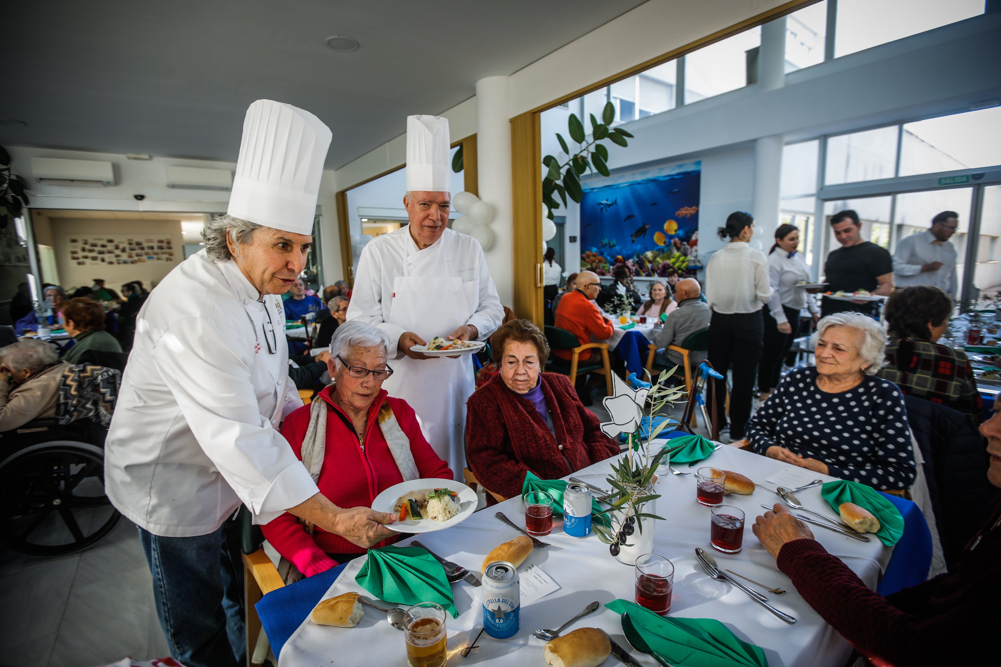 Los chefs Tony Parra y Miguel Ayala sirven los platos a los mayores de la residencia.