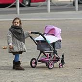 Una niña, con un carrito de bebé en la capital granadina.