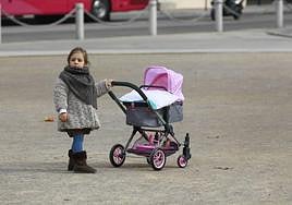 Una niña, con un carrito de bebé en la capital granadina.