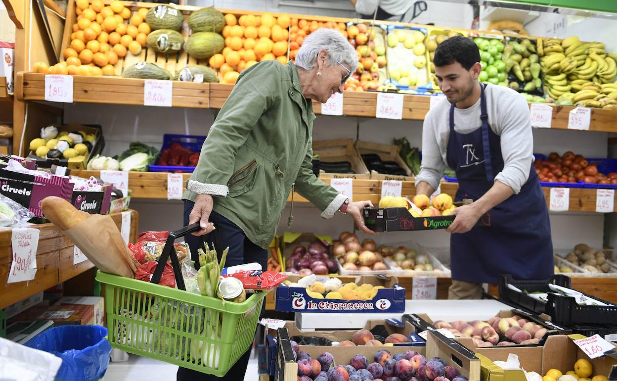 Clienta en un supermercado jutno al tendero. 