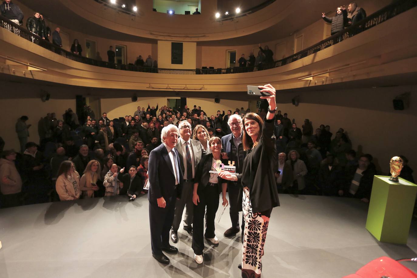 Autofoto en el escenario de los participantes en el foro, con la Copa del Mundo expuesta a la izquierda. 