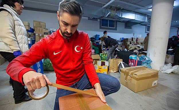 Un voluntario con la bandera turca en la sudadera cierra una caja con ayuda humanitaria. 