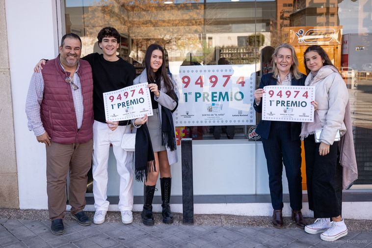 Damián (a la izquierda del todo), junto a su familia en el estanco que ha vendido el primer premio del Niño.