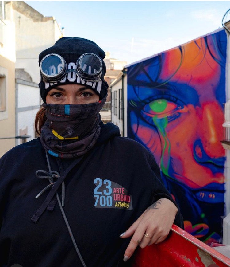 MaríaDie posa ante la obra que pintó en Linares seleccionada por Street Art Cities.