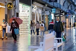 Varias personas pasean en una calle comercial.