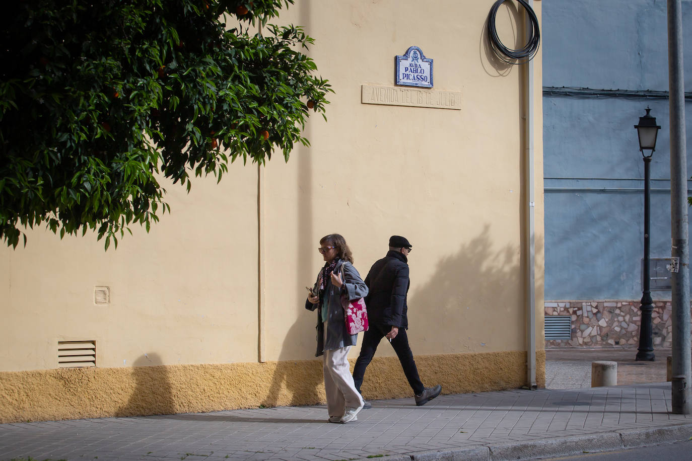 Transeúntes por debajo de las placas de la Calle Pablo Picasso y Avenida del 18 de julio.