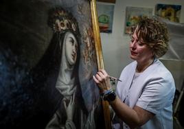 Eva María García, junta al cuadro de Santa Rosa de Lima que ha restaurado en su taller.