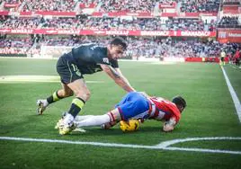 Carlos Neva cae al césped en un lance con Marc Pubill durante el partido entre Granada y Almería el pasado mes de febrero en Los Cármenes.
