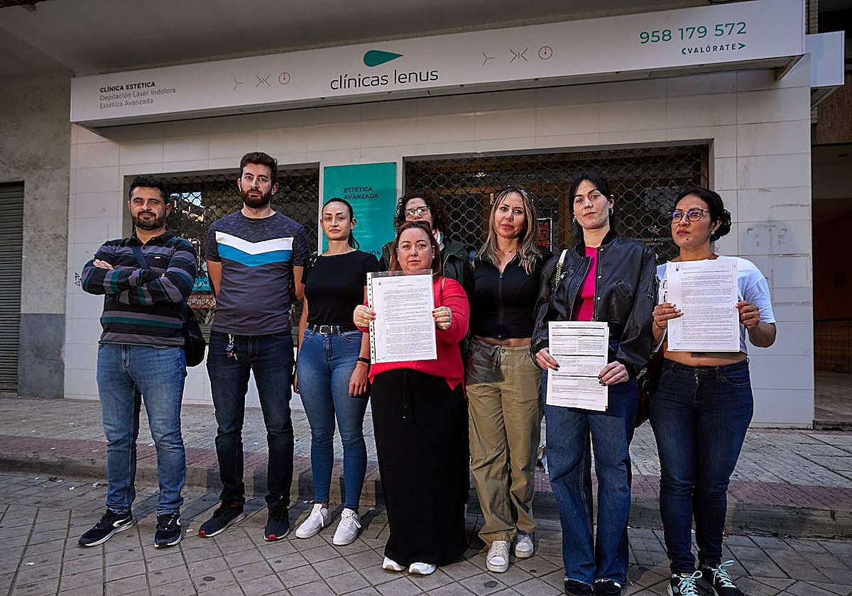 Varios afectados por el cierre de la clínica de láser posan delante del local, con la persiana bajada.