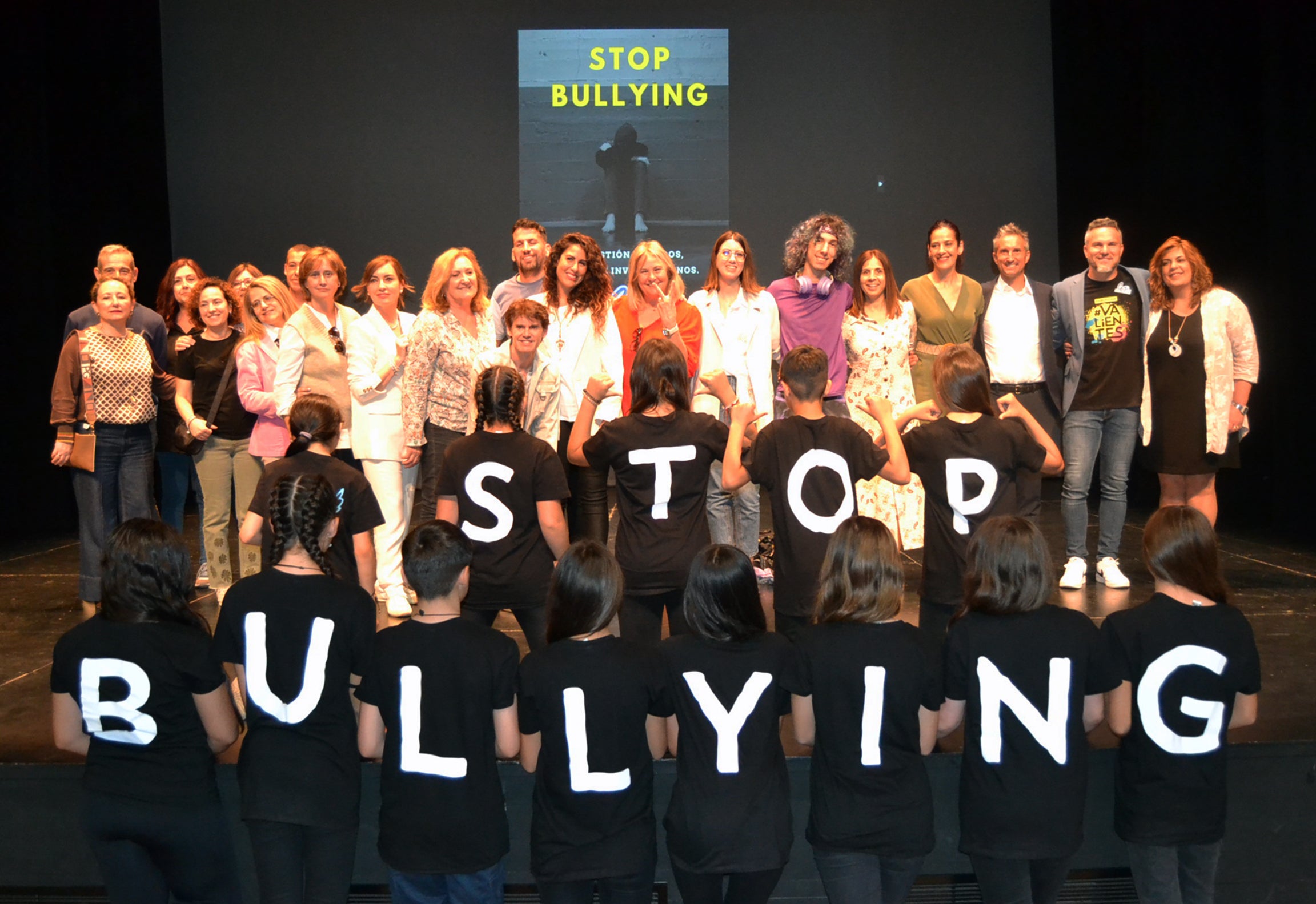 Maestros, alumnos y otros participantes en la gala posan en el escenario con un mensaje claro en las camisetas de los escolares.