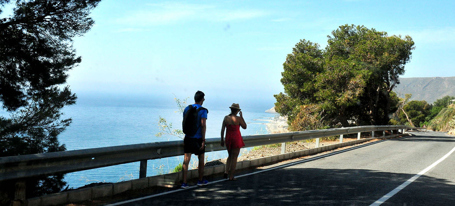 Dos personas caminan por la N-340, entre Castell de Ferro y El Lance.
