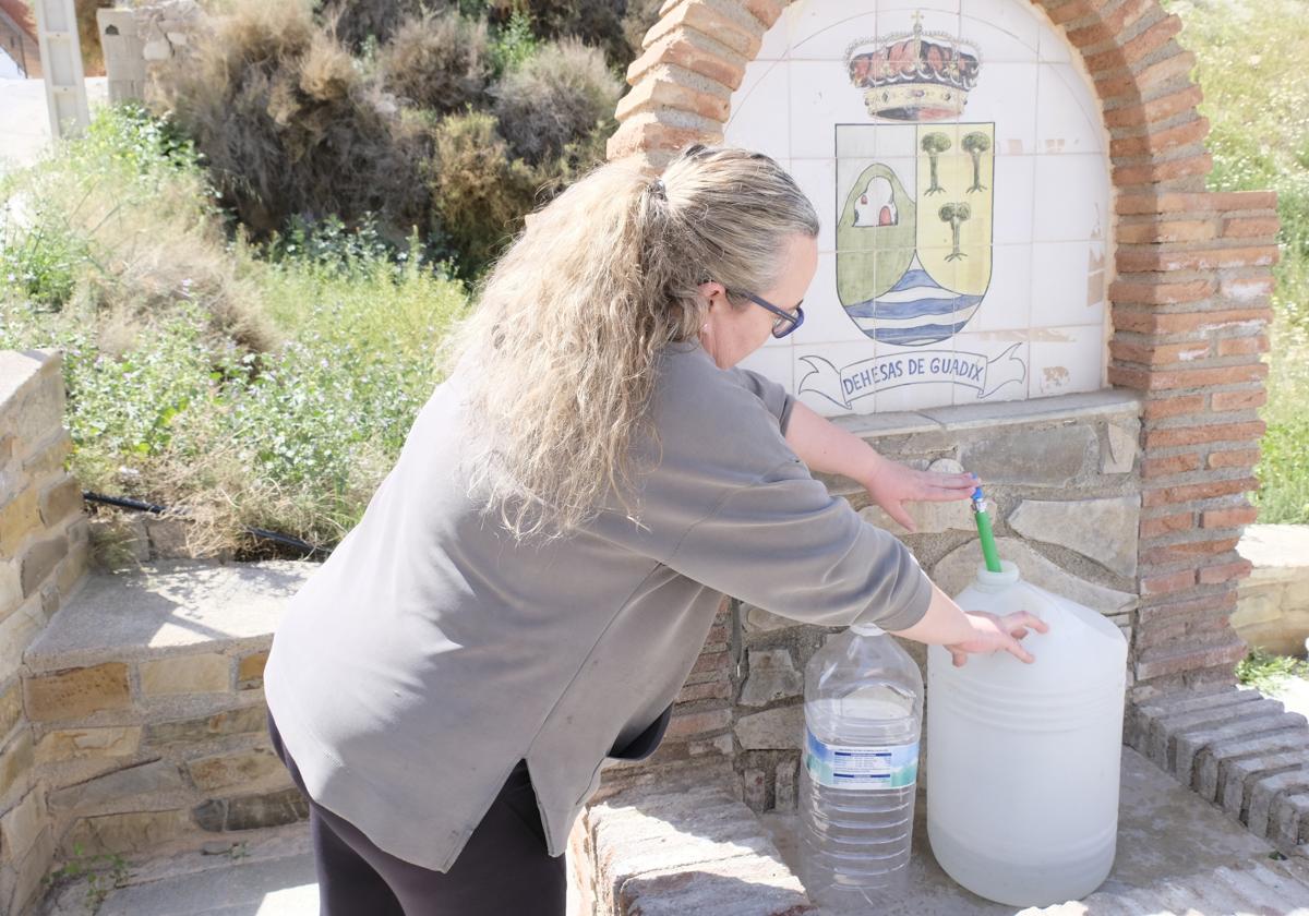 Vecinos de Dehesas mientras rellenan las botellas en la fuente