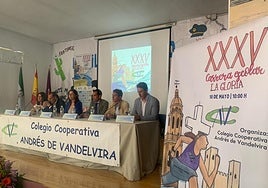 El cartel que anuncia la prueba de este año junto a la mesa donde están representantes del centro y de las administraciones colaboradoreas.