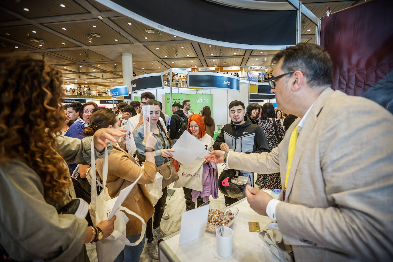 Candidatos interesados en el expositor de la empresa Arquisocial en la feria de empleo.