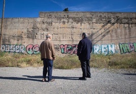 Dos lugareños observan las pintadas en la Muralla de la Alberzana.