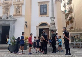 Agentes de la Policía Local explican a los chavales en el acceso a la iglesia de la plaza de Gracia la situación para que tengan cuidado.