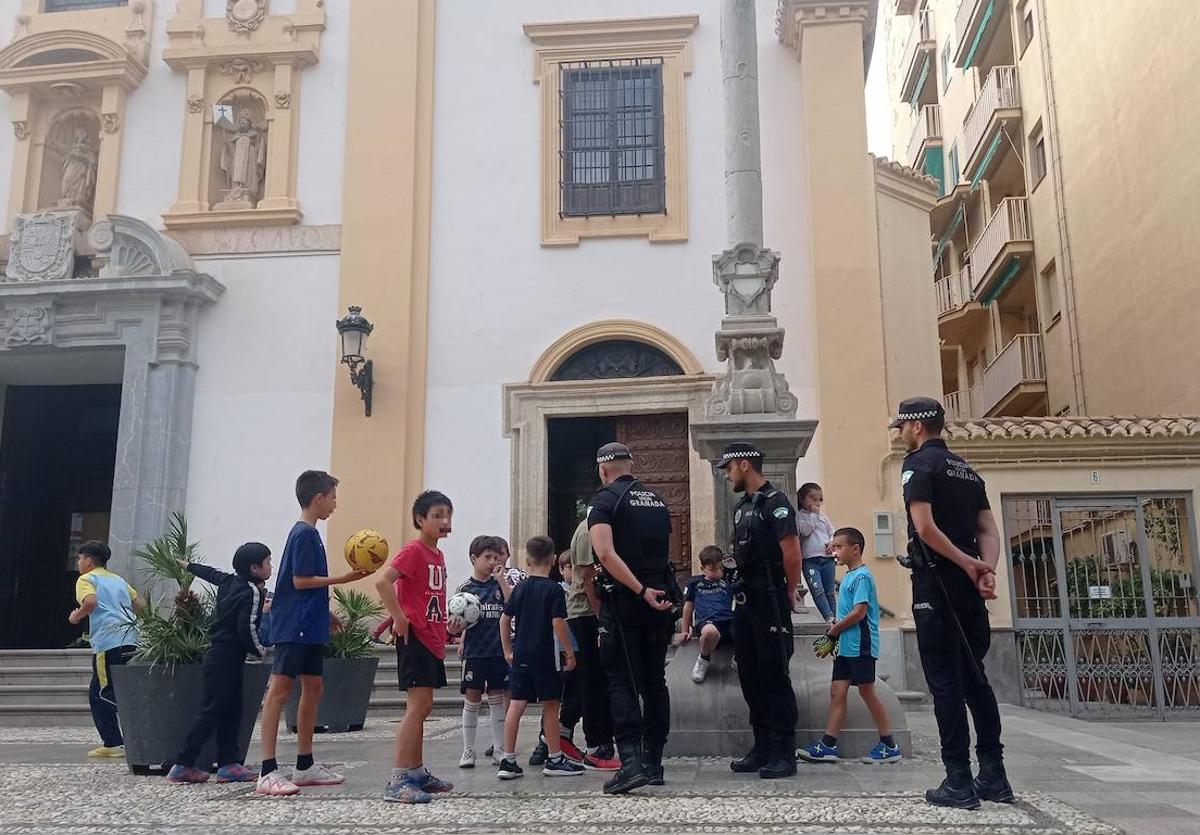 Agentes de la Policía Local explican a los chavales en el acceso a la iglesia de la plaza de Gracia la situación para que tengan cuidado.