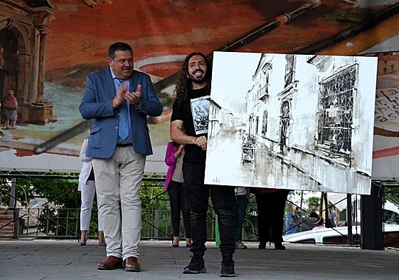 El ganador Carlos Montoro sostiene la obra.