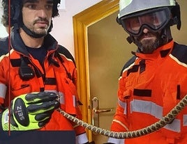 Dos bomberos sostienen la serpiente encontrada en el baño de una familia de Guadix.