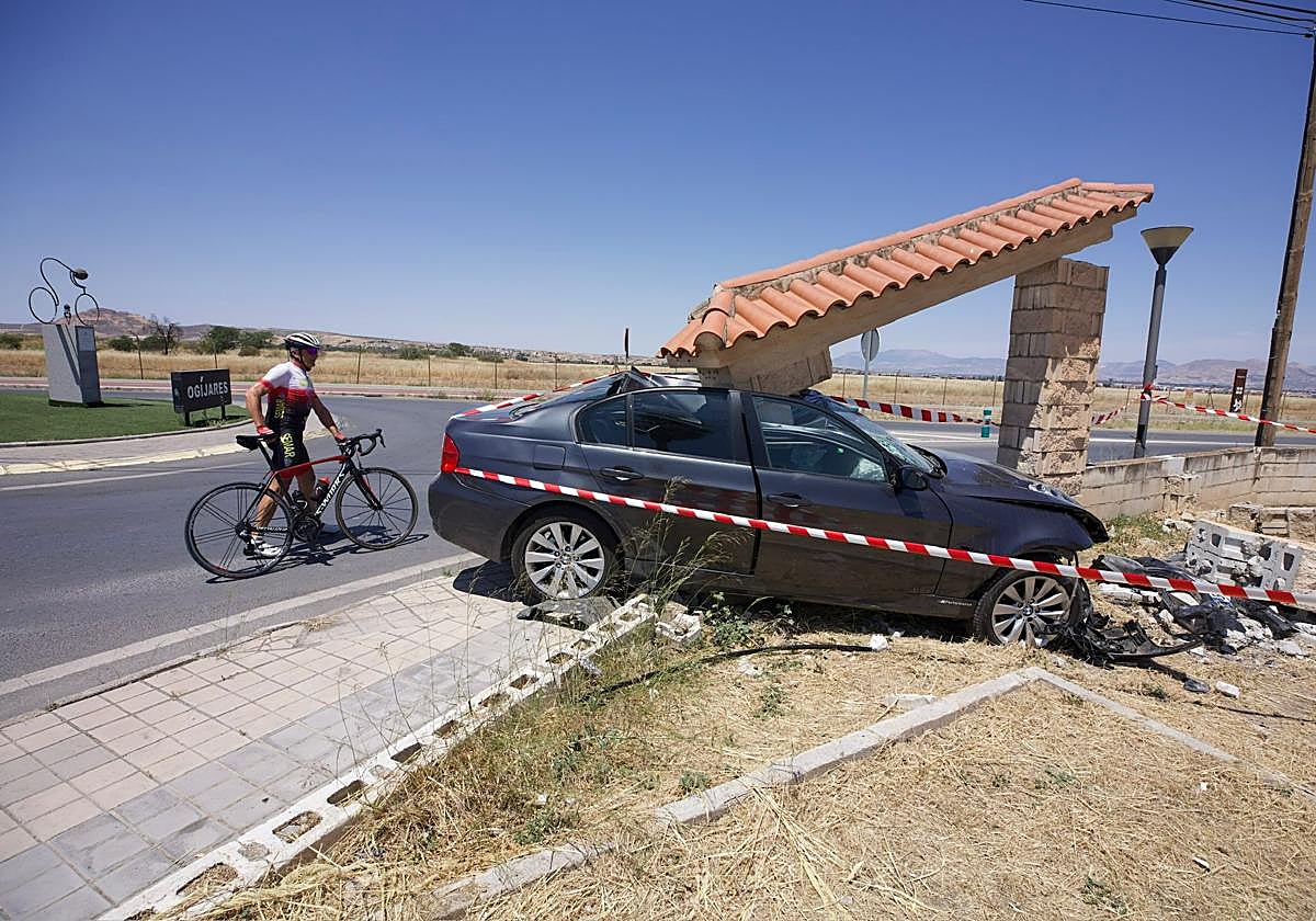 Un ciclista observa el coche siniestrado en Ogíjares.
