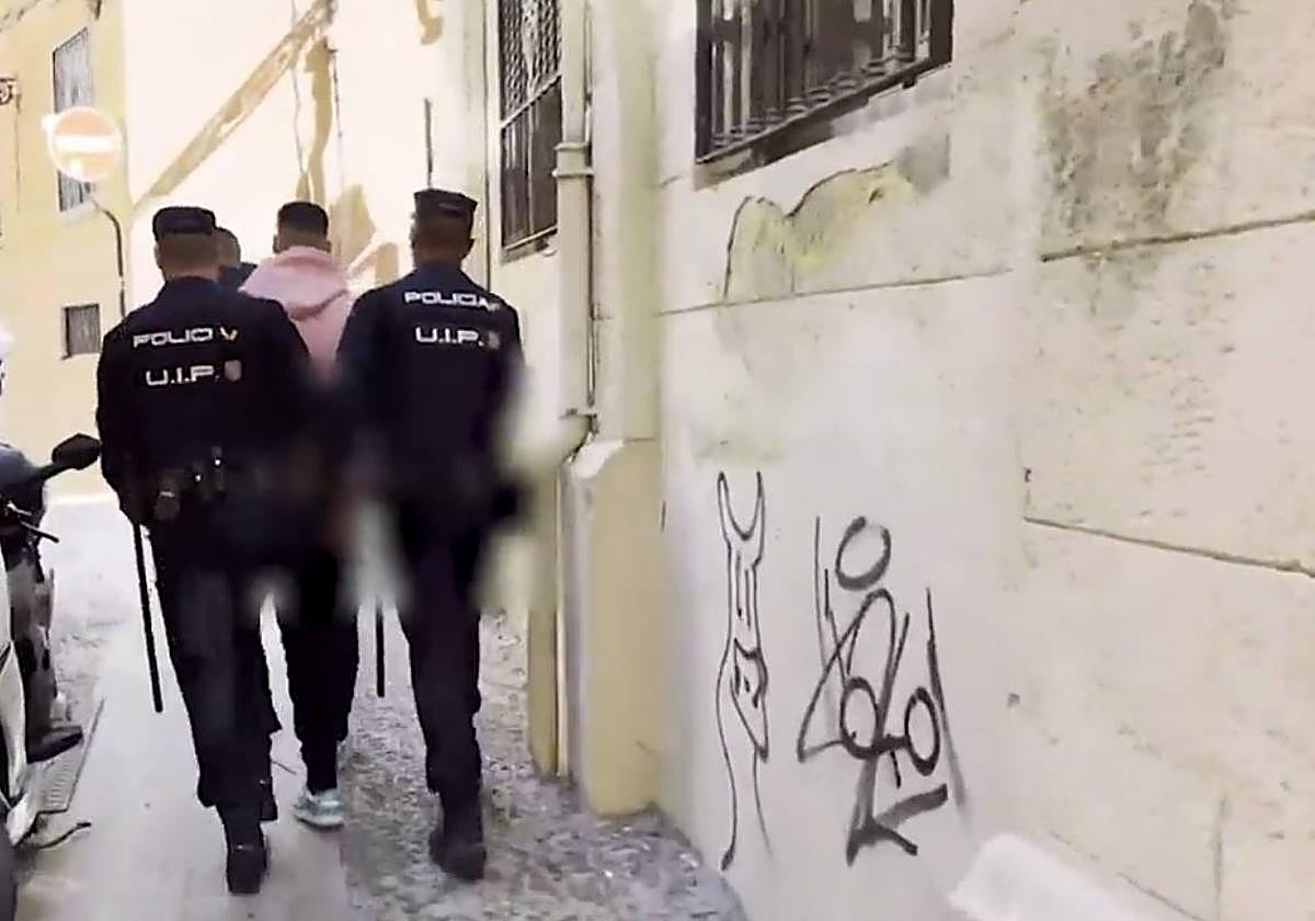 Agentes de la UIP de la Policía Nacional llevándose detenido a uno de los miembros del 'coro 717'.