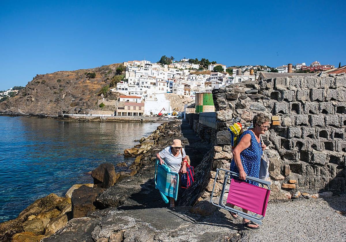 Bañistas atraviesan la escollera de La Caleta para llegar a la arena.