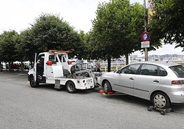 Una grúa municipal retira un vehículo en una ciudad española.