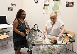 Una mujer llena la cesta de la compra con las donaciones.