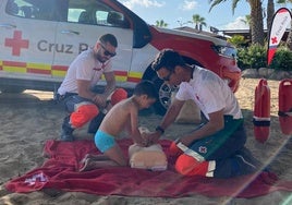 Un niño aprende RCP en la playa.