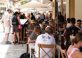 Turistas repasan la lista de precios de la carta de un restaurante.