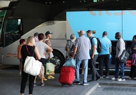 Un grupo de personas a la espera de subirse a un autobús para iniciar sus vacaciones.