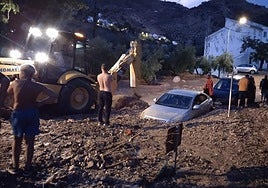 Una grúa intenta rescatar un vehículo mientras los vecinos observan