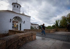 Dos vecinos cruzan el puente de la localidad pinera tras haber sido fumigado.