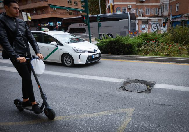 Un patinete cruza junto al socavón