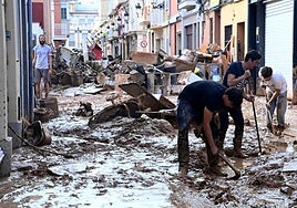 Un grupo de personas limpian una calle de Paiporta.