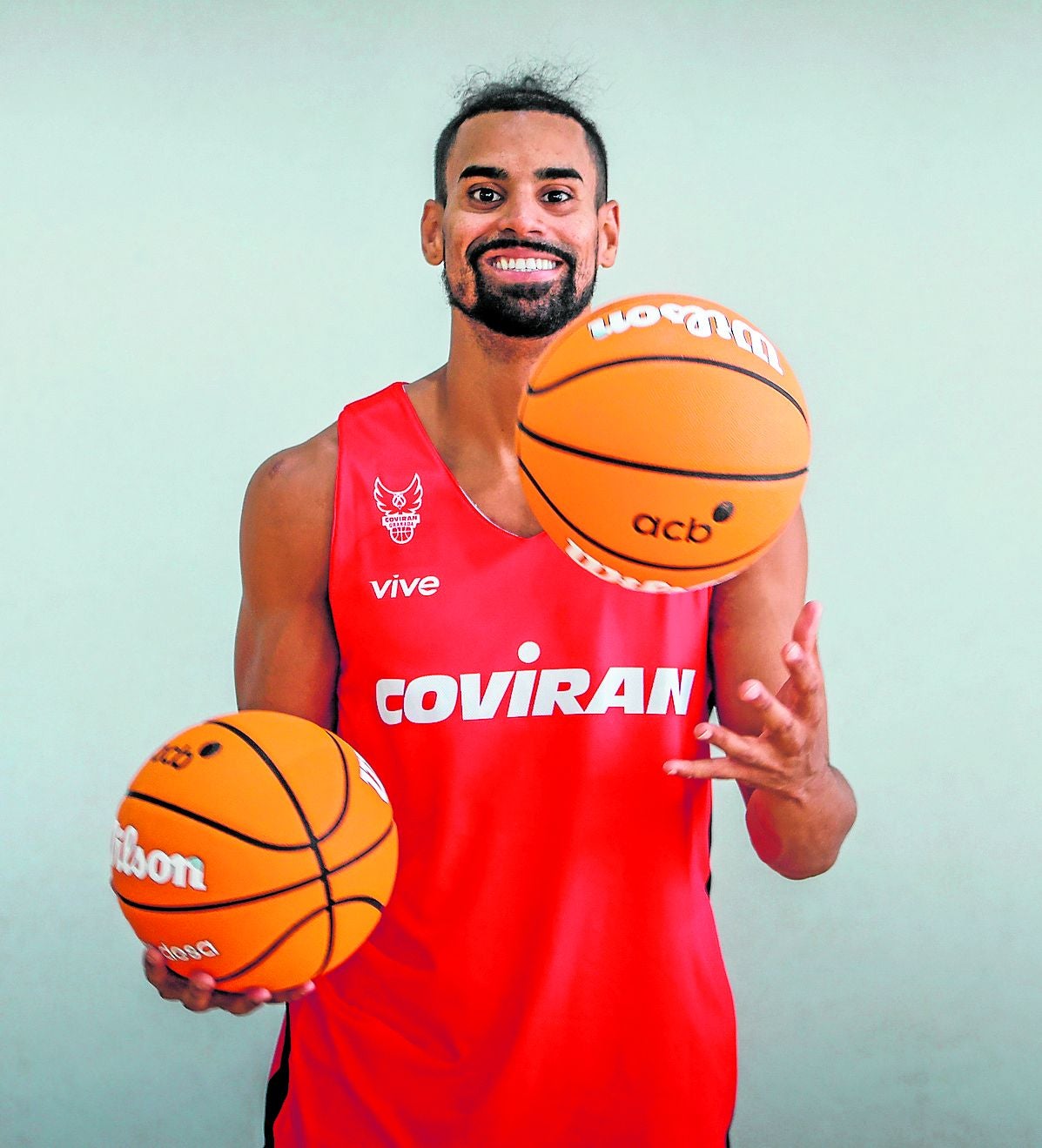 El rojinegro Gian Clavell eleva los balones de competición mientras sonríe a la cámara.