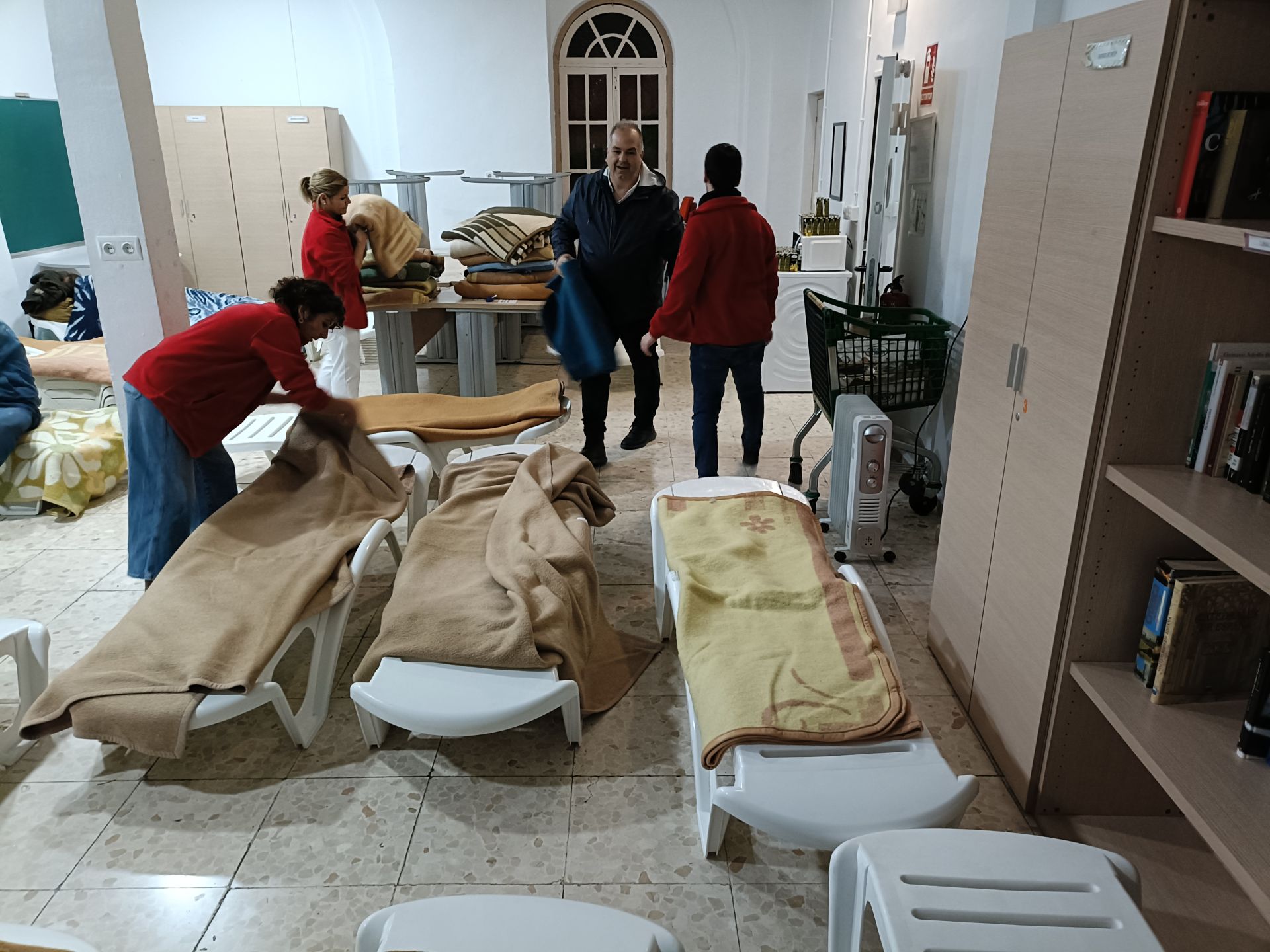 El director, el conserje y las dos trabajadoras sociales de la Casa de Cogida Madre de Dios preparan las mantas en las hamacas.