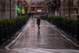 Una mujer cruza Ganivet bajo la lluvia, este miércoles.