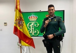 José posa con su medalla junto a la bandera nacional y su uniforme de la Benemérita.