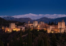 La Alhambra, iluminada con Sierra Nevada al fondo desde la torre de la iglesia de Santa María de la Aurora y San Miguel.