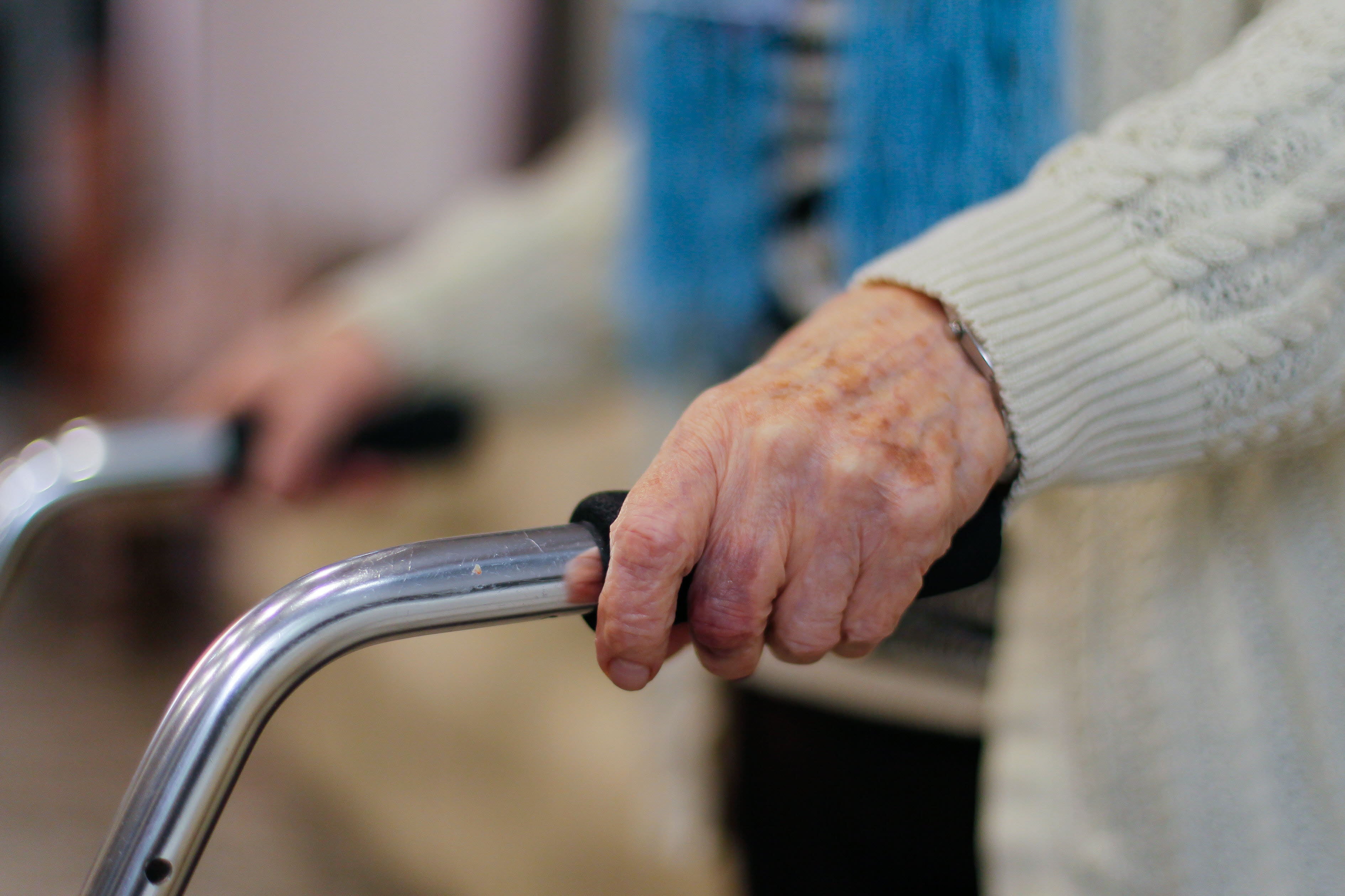 Una anciana camina con la ayuda de un andador.