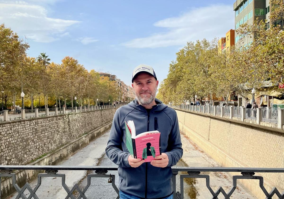 Alejandro Pedregosa posa con su último libro, 'Comadrejas', en el puente de San Antón, sobre el Genil.