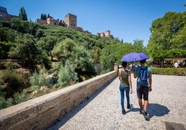 Una pareja pasea al sol bajo una sombrilla en una imagen de archivo.