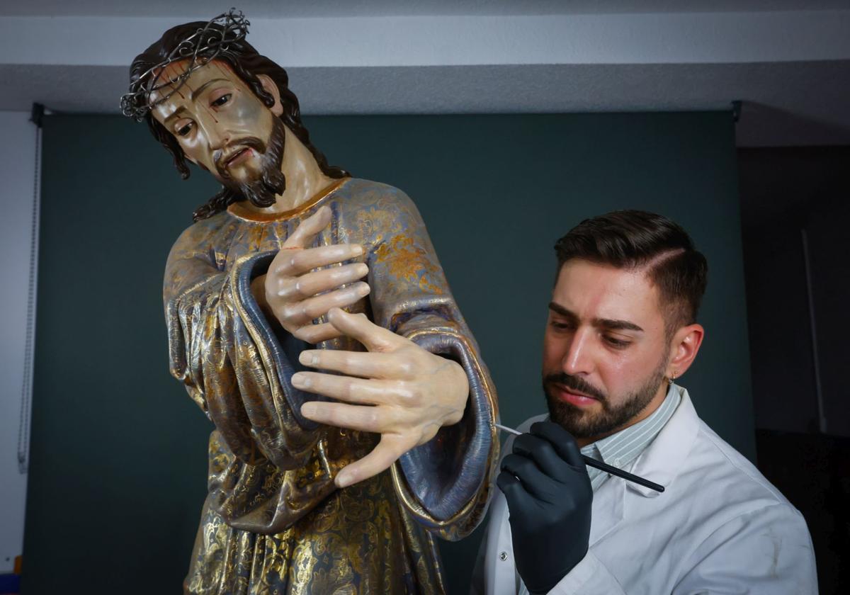 Julio Alcaraz revisa la manga del Cristo, ya con su esplendor original.