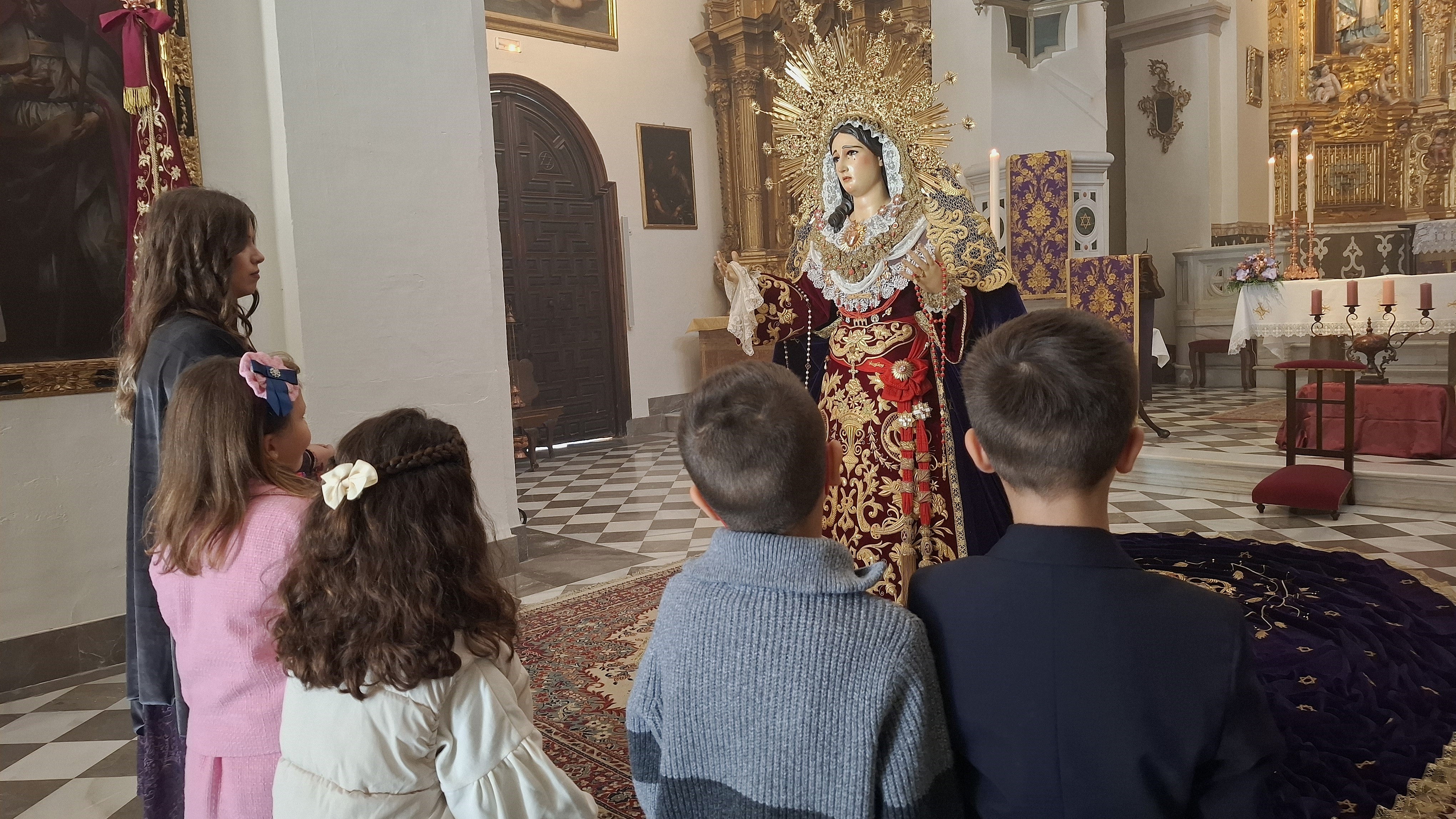 Niños rezan ante la recién restaurada Virgen del Sacromonte en la abadía.