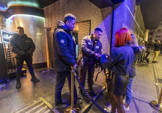 Porteros de una discoteca de Granada inspeccionan el interior del bolso de una clienta.