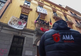 Okupas en el balcón y, debajo, un trabajador de la empresa granadina de desalojo.