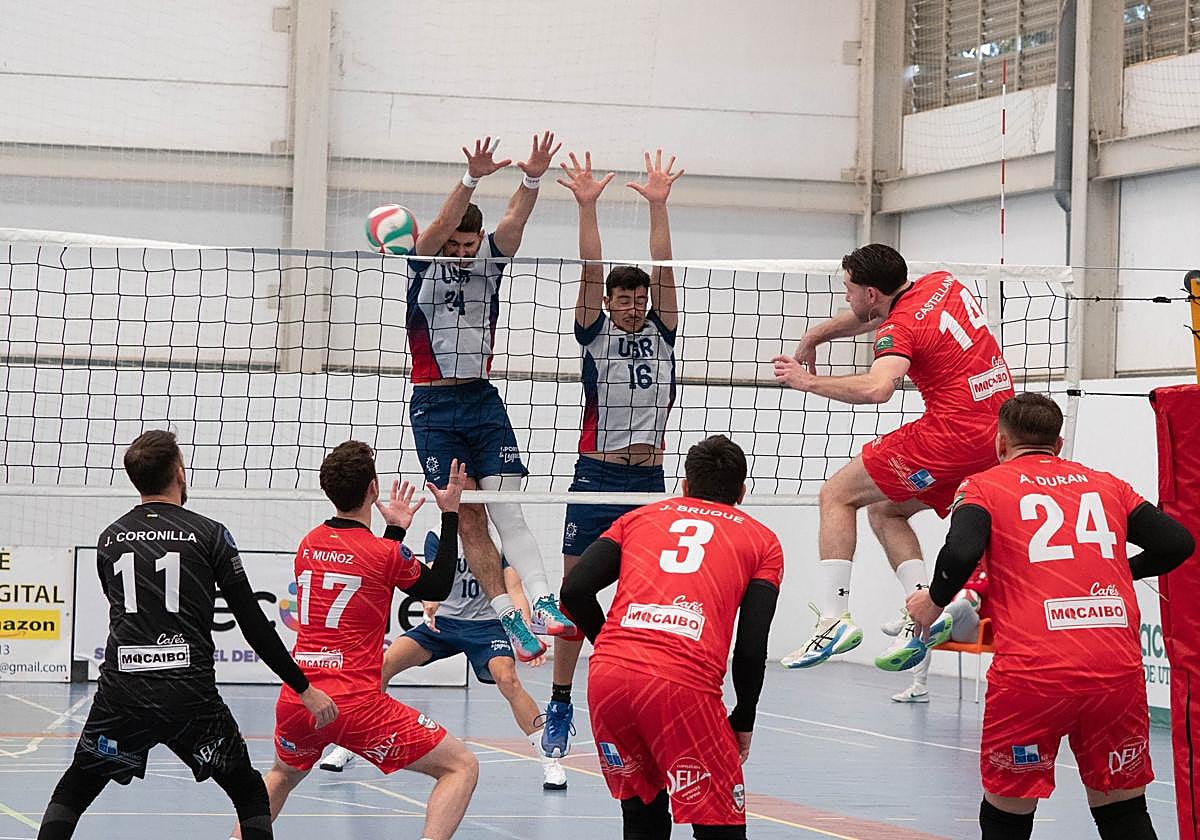 Dos jugadores del 'Uni' saltan para bloquear un remate del Utrera.